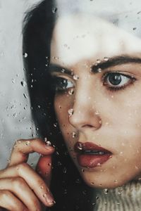 Close-up of woman by wet glass