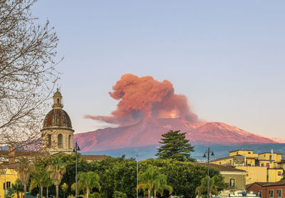 Low angle view of the cityscape against the sky during the strombolian eruption of etna