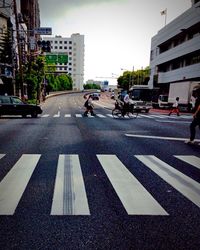 Cars on road in city against sky