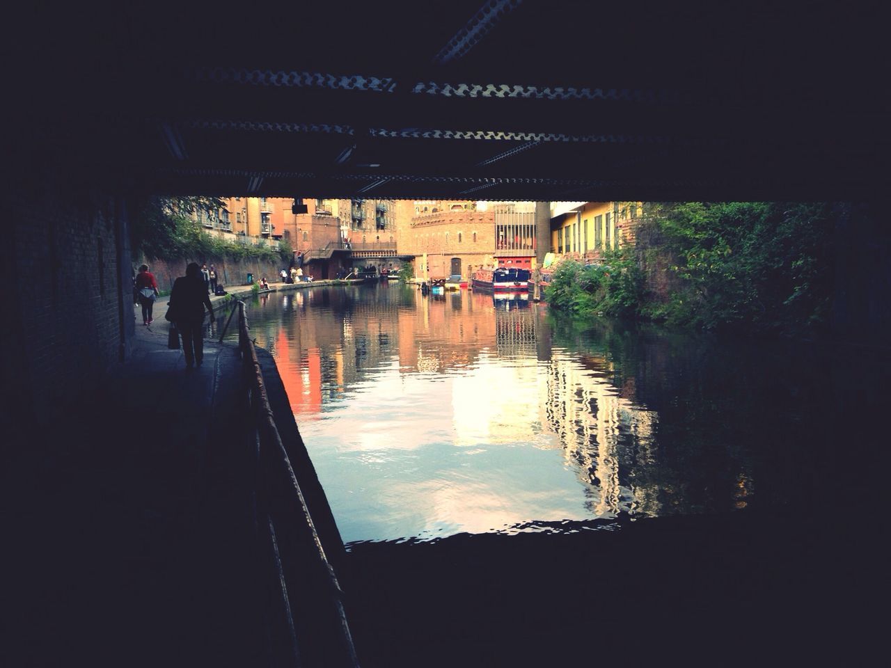 water, men, lifestyles, architecture, built structure, person, leisure activity, reflection, transportation, walking, silhouette, building exterior, large group of people, bridge - man made structure, medium group of people, travel, unrecognizable person, mode of transport, river