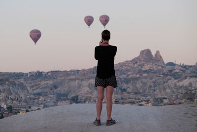 Rear view of woman standing on rock against sky