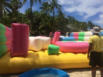 Rear view of man standing by bouncy castle at beach