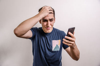 Young man using mobile phone against white background