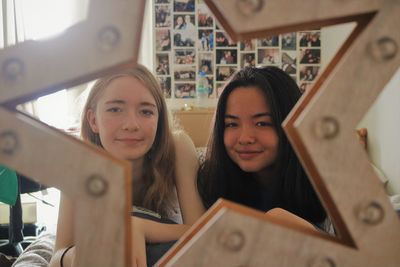 Portrait of smiling friends lying on bed at home