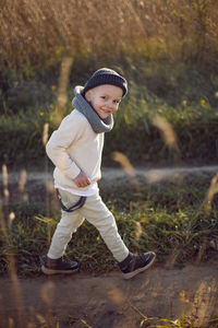 Funny fashionable boy child stands on the field in autumn