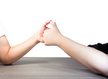 Midsection of couple holding hands over white background