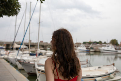 Rear view of woman at harbor against sky
