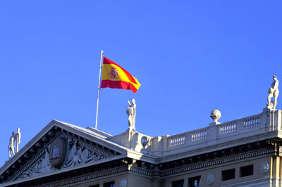 Low angle view of flag on building against blue sky