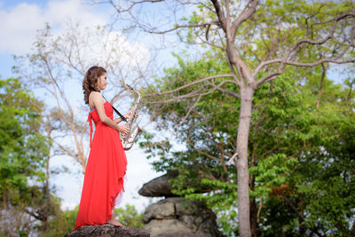 Woman standing by plants against trees