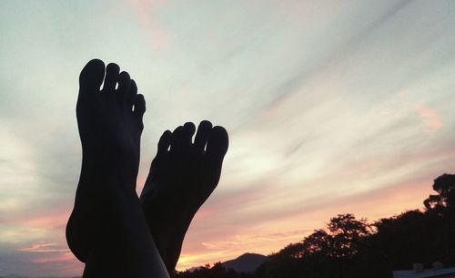 Close-up of silhouette hand against sky during sunset