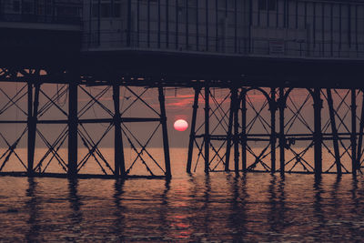 Reflection of silhouette bridge in water at sunset