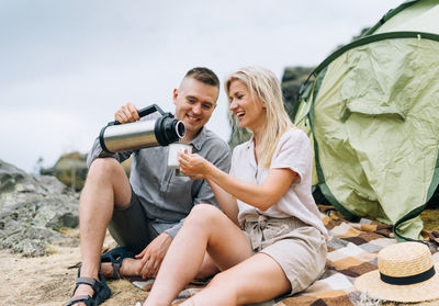 Couple enjoying coffee by tent in campsite