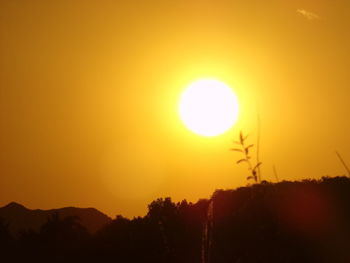 Silhouette landscape against orange sky