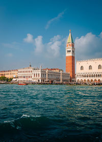 Buildings by river against sky