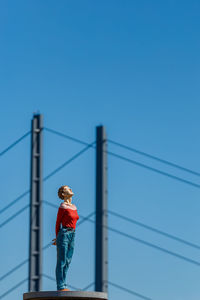 Rear view of person standing on bridge against clear blue sky