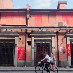 People riding bicycle on street against building