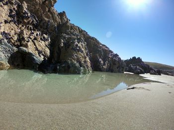 Rock formation on beach against sky