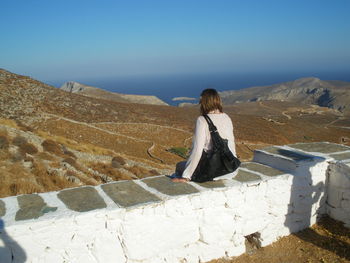 Rear view of woman against mountains against clear sky