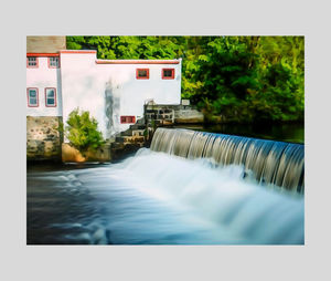 Scenic view of waterfall by building against sky