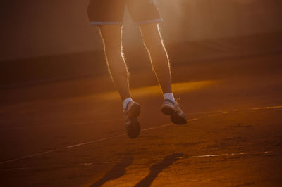 Low section of man jumping at tennis court