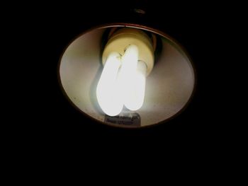 Low angle view of illuminated light bulb against black background