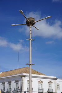 Low angle view of windmill by building against sky