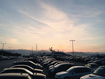 Cars in parking lot against sky during sunset