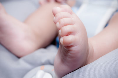 Close-up of baby holding hands on bed