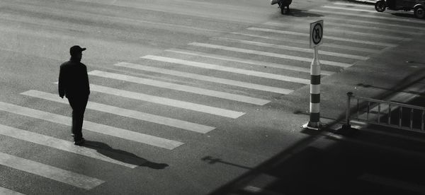 Rear view of man crossing road
