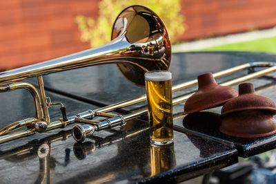 Close-up of trombone by beer glass on table