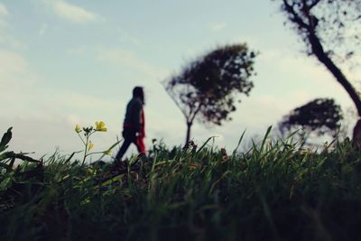 Woman walking on field against sky