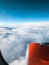 Airplane flying over cloudscape against blue sky