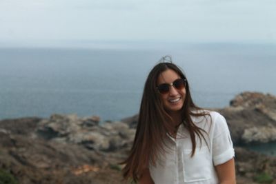 Portrait of woman smiling while standing on rocky shore