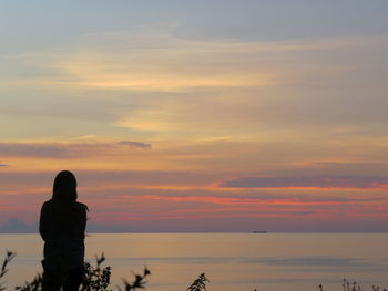 Silhouette person looking at sea against sky during sunset