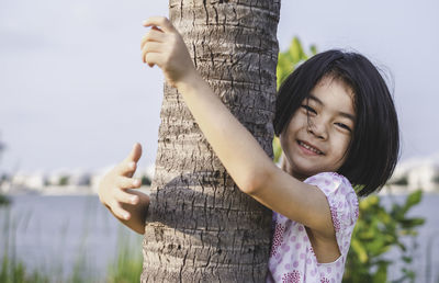 Portrait of a smiling girl on tree trunk