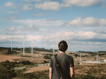 Asian man travel stand pose and see to sky for wait his girlfriend with wind turbine background