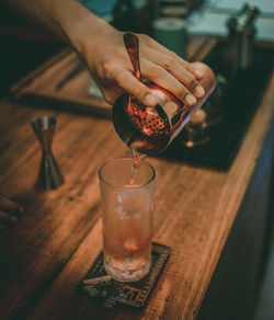 Close-up of hand pouring wine in glass on table