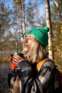 Portrait tourist woman hiker camper drinking hot tea from cup enjoying resting on nature.