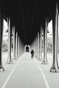 Rear view of man cycling under bridge