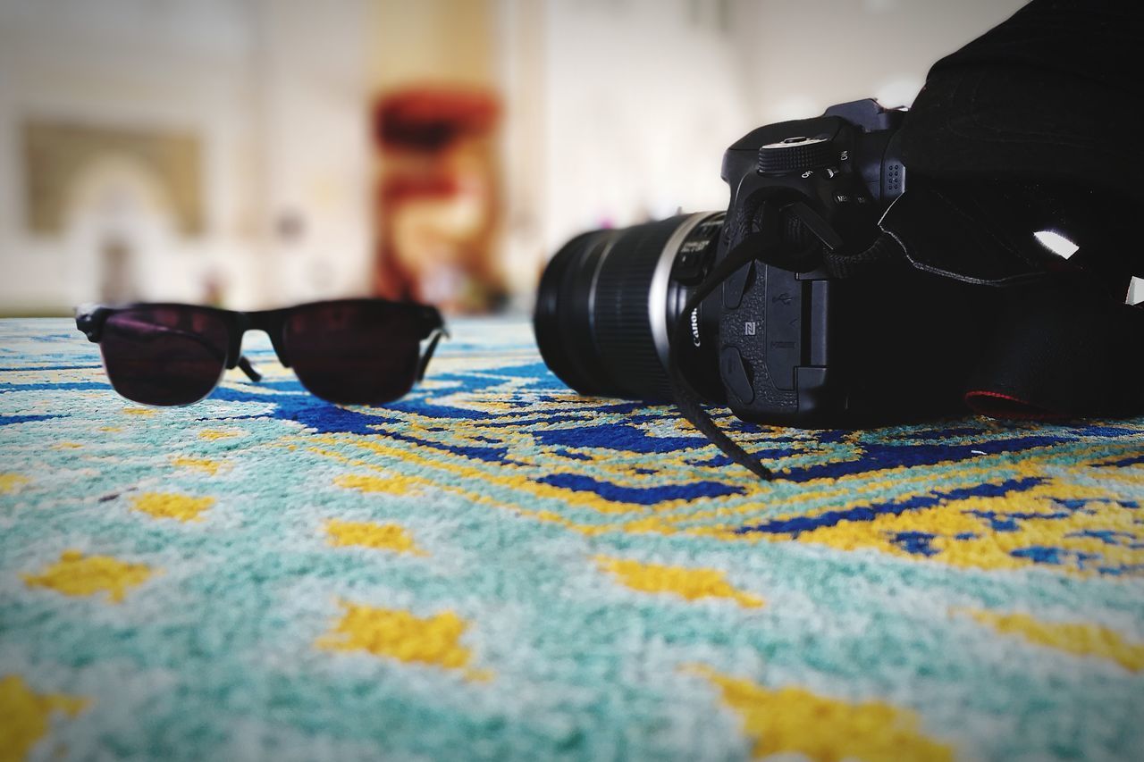 CLOSE-UP OF CAMERA ON TABLE WITH EYEGLASSES