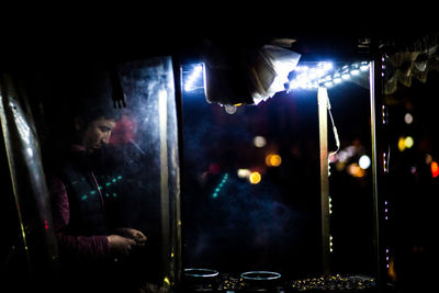 Woman seen through glass window at night