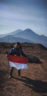 Man holding indonesian flag while standing on mountain