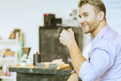 Side view of smiling man having coffee at cafe