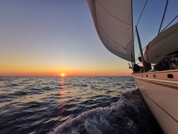 Sailboat sailing on sea against sky during sunset