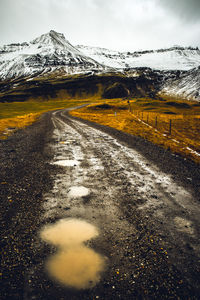 Road leading towards snowcapped mountain against sky