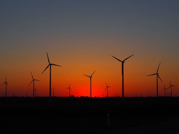 Silhouette wind turbine against sky during sunset