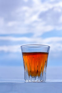 Close-up of beer glass on table against sky