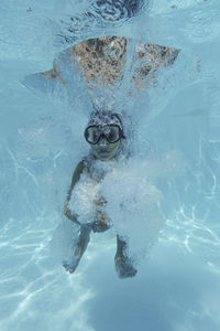 Little girl jumping into a pool and diving