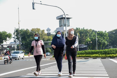 Rear view of people walking on road in city