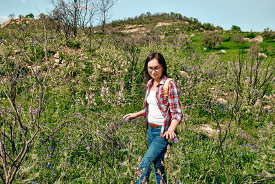 Happy carefree woman walking on a spring meadow with beautiful field flowers. hiking outdoors